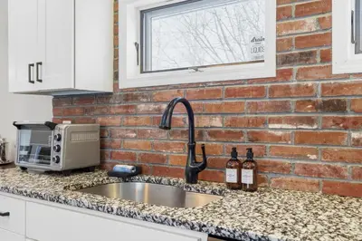 a kitchen counter with a sink and a brick wall at The Rock Oak Escape in Dingmans Ferry