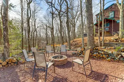 a group of chairs sitting around a fire pit in the woods at 5 Mi to Jack Frost Skiing Walkable Family Home in Lake Harmony