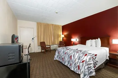a hotel room with a bed and a flat screen tv at Red Roof Inn & Suites Hazleton in Hazleton