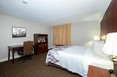 a hotel room with a bed and a desk and a computer at Red Roof Inn & Suites Hazleton in Hazleton