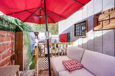 a red umbrella sitting on a patio with a couch at Upper Clinton Hill Studio! Walk to Eats and Shops in Newark