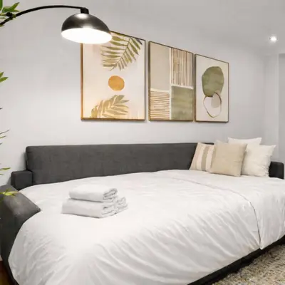a bedroom with a large white bed with four pictures on the wall at Hip NYC Hideaway in Lively East Village in New York