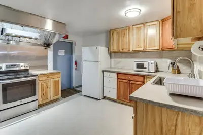 a kitchen with white appliances and wooden cabinets at 4 Mi to Mauch Chunk Lake Spacious Apt with Bar! in Summit Hill