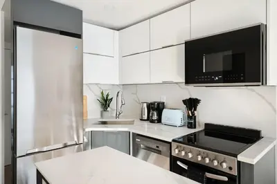 a kitchen with white cabinets and a stove top oven at 22nd Sleek Modern 1BR Gramercy in New York