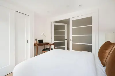 a white bedroom with a bed and a desk at 22nd Sleek Modern 1BR Gramercy in New York