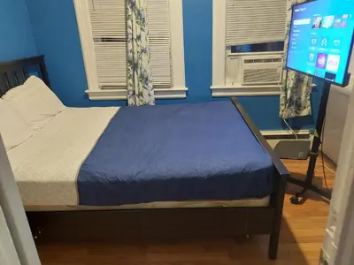 a bedroom with a bed with a blue wall and windows at Grove#5 in Irvington
