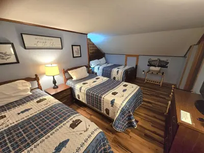 a room with three beds and a lamp in it at 4BR Cabin by the Lake with Hot Tub, Game Room, Fire Pit in Lake Harmony