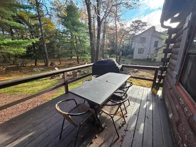 a picnic table and two chairs on the porch of a house at 4BR Cabin by the Lake with Hot Tub, Game Room, Fire Pit in Lake Harmony