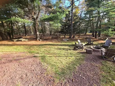 a group of chairs in a field with trees at 4BR Cabin by the Lake with Hot Tub, Game Room, Fire Pit in Lake Harmony