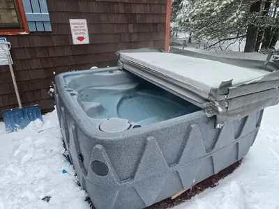 a tub sitting in the snow next to a house at 4BR Cabin by the Lake with Hot Tub, Game Room, Fire Pit in Lake Harmony