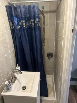 a bathroom with a blue shower curtain and a sink at 1052grovest #3 in Irvington