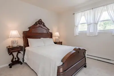 a bedroom with a large bed and two windows at Catskill gem! Four bedroom on 20 quiet acres in Barryville