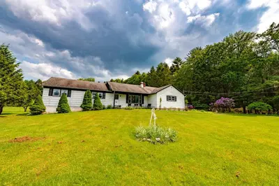 a white house in a field with a grass yard at Catskill gem! Four bedroom on 20 quiet acres in Barryville
