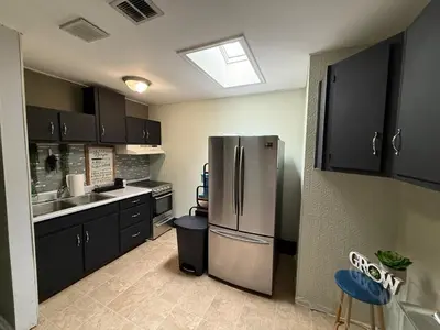 a kitchen with black cabinets and a stainless steel refrigerator at Happy House in the City in Harrisburg