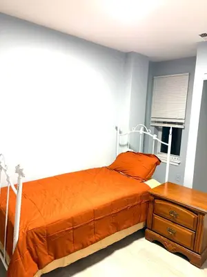 a bedroom with an orange bed and a nightstand at 5 bedrooms 2 bathrooms furnished home in Philly near Temple University in Philadelphia
