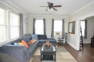 a living room with a blue couch and a ceiling fan at Cozy Beds with Parking, Laundry - Near RU, RWJ, NJ Transit in Highland Park