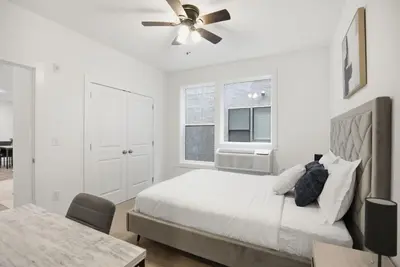a white bedroom with a bed and a ceiling fan at Cozy 1BR home inside the Fairmount Square building in Philadelphia