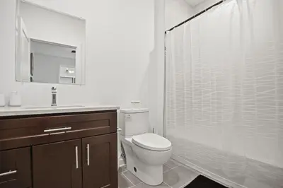 a white bathroom with a toilet and a shower at Cozy 1BR home inside the Fairmount Square building in Philadelphia
