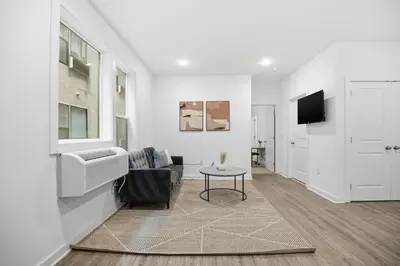 a white living room with a couch and a tv at Cozy 1BR home inside the Fairmount Square building in Philadelphia