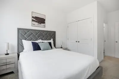 a white bedroom with a large white bed with blue pillows at Bright 1BR unit in the Fairmount Square building in Philadelphia