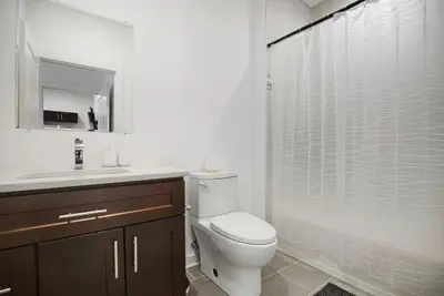 a white bathroom with a toilet and a shower at Bright 1BR unit in the Fairmount Square building in Philadelphia