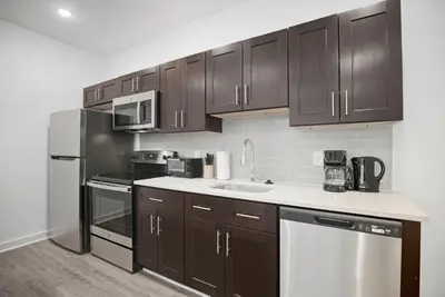 a kitchen with brown cabinets and a sink and a refrigerator at Cozy and bright 1BR located in Fairmount Square in Philadelphia