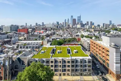 a building with a green roof with a city in the background at Simple, modern 1BR in Fairmount Square in Philadelphia