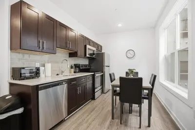 a kitchen with wooden cabinets and a table with chairs at Simple, modern 1BR in Fairmount Square in Philadelphia