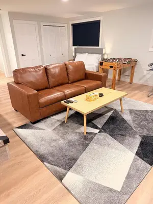 a living room with a brown couch and a coffee table at Huge Private Suite with Pool Table, Sauna & Fire Pit in Ellenville