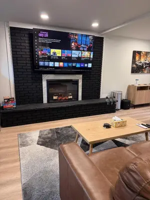 a living room with a fireplace with a tv on the wall at Huge Private Suite with Pool Table, Sauna & Fire Pit in Ellenville