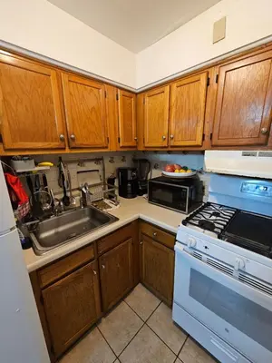 a kitchen with wooden cabinets and a stove and a sink at Clientele in North Bergen