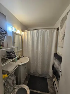 a bathroom with a white shower curtain and a sink at Clientele in North Bergen