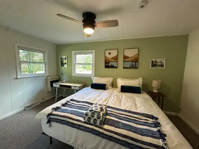 a bedroom with a large bed with a ceiling fan at Riverfront Poconos Cabin with Hot Tub on 4 Acres Near Delaware River (Sleeps 6) in Lackawaxen