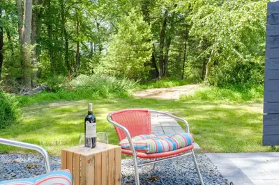 a bottle of wine sitting on a table with a chair at Riverfront Poconos Cabin with Hot Tub on 4 Acres Near Delaware River (Sleeps 6) in Lackawaxen