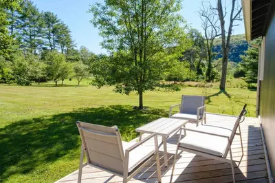 two chairs and a table on a porch with a field at Riverfront Poconos Cabin with Hot Tub on 4 Acres Near Delaware River (Sleeps 6) in Lackawaxen
