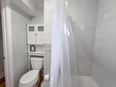 a white bathroom with a toilet and a shower at South Philly Retreat with Movie Nights and Backyard BBQ in Philadelphia