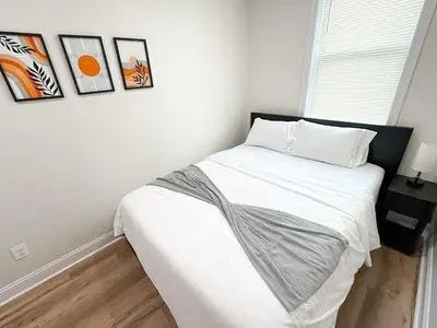 a bedroom with a bed with white sheets and pictures on the wall at South Philly Retreat with Movie Nights and Backyard BBQ in Philadelphia