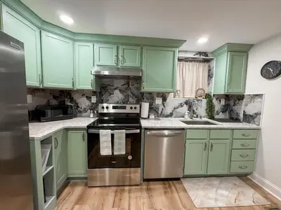 a kitchen with green cabinets and a stove top oven at South Philly Retreat with Movie Nights and Backyard BBQ in Philadelphia