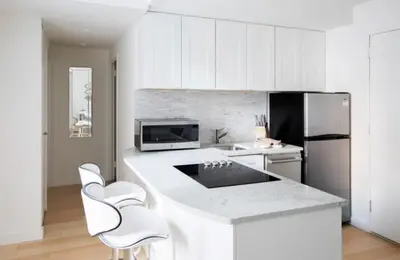 a white kitchen with white cabinets and a refrigerator at Executive Plaza in New York