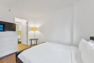 a white bedroom with a bed and a tv at Nash in New York