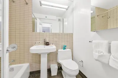a white bathroom with a toilet and a sink at Nash in New York