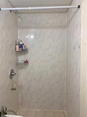 a bathroom with a shower with a tiled wall at Near Seaport In Chinatown in New York