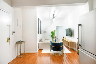 a living room with white walls and a blue chair at Prime location 1BR Newly Furnished in New York