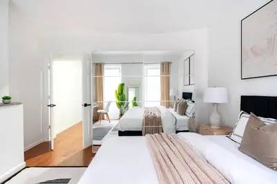 a white bedroom with two beds and a mirror at Prime location 1BR Newly Furnished in New York
