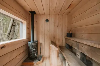 a wooden cabin with a fireplace and a window at Creekside Modern Cabin Sauna Hot Tub Niksen Den in Callicoon