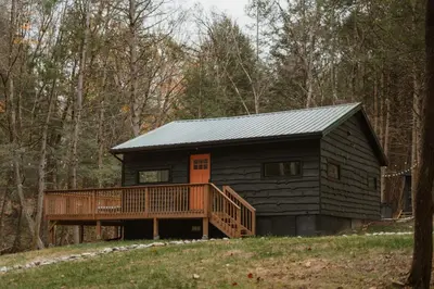 a log cabin in the woods with a deck at Creekside Modern Cabin Sauna Hot Tub Niksen Den in Callicoon