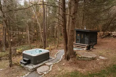 a bath tub sitting next to a tree in the woods at Creekside Modern Cabin Sauna Hot Tub Niksen Den in Callicoon
