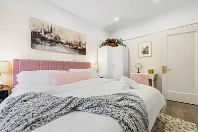 a bedroom with a large white bed with a pink headboard at FIFA26|Based Btwn MetLife & Manhattan|Parking in Bayonne