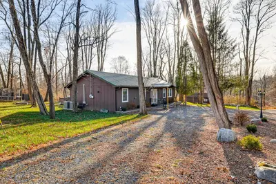 a house in the woods with a gravel road in front at Pet-Friendly Group Getaway 12 Mi to Camelback Mtn! in Cresco