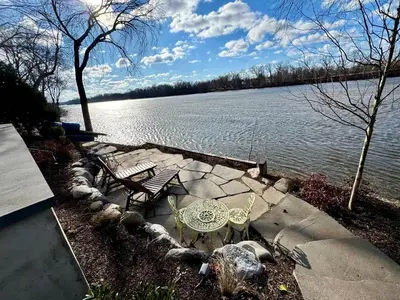 a picnic table and benches next to a lake at Charming Historic Riverfront Home with Garden Views near Lambertville, New Jersey in Titusville